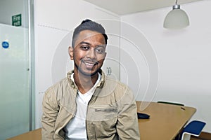 Young Indian man smiling at camera in his office