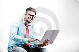 Young Indian man on spectacles and using laptop