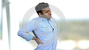 Young Indian man suffering from back ache.