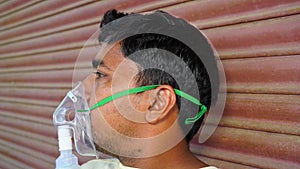 Young Indian man taking Emergency Oxygen with Cannula outside of hospital. Severe causes due to Covid in India concept