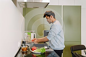 Young indian man washing vegetables to cook salad