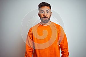 Young indian man wearing orange sweater over isolated white background puffing cheeks with funny face