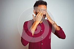 Young indian man wearing red elegant shirt standing over isolated grey background rubbing eyes for fatigue and headache, sleepy