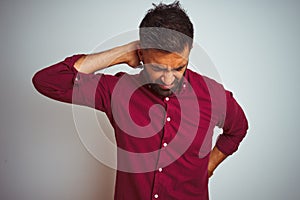 Young indian man wearing red elegant shirt standing over isolated grey background Suffering of neck ache injury, touching neck