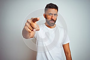 Young indian man wearing t-shirt standing over isolated white background pointing displeased and frustrated to the camera, angry