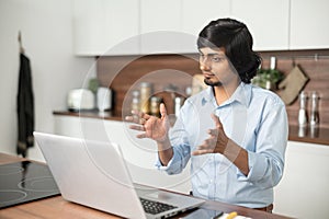 Young indian man wearing talks online using laptop computer for video connection