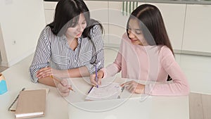 Young indian mom and schoolgirl doing home work online together at home.