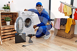 Young indian technician working on washing machine with a happy and cool smile on face