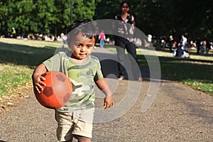 A Young Indian Toddler running with red ball