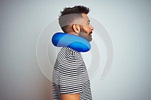 Young indian tourist man on travel wearing neckpillow over isolated white background looking to side, relax profile pose with
