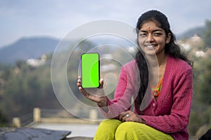 Young indian village girl showing a mobile phone with green screen