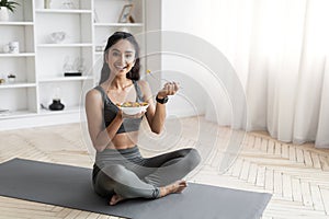 Young indian woman eating healthy salad after workout