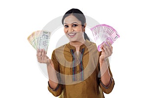 Young Indian woman holding currency notes agianst white