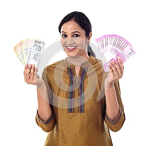 Young Indian woman holding currency notes agianst white