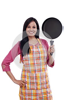 Young Indian woman holding kitchen utensil against white