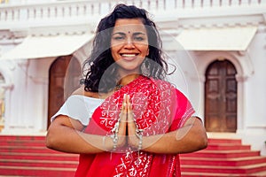 Young Indian woman in traditional sari red dress praying in a hindu temple goa india Hinduism.girl performing namaste