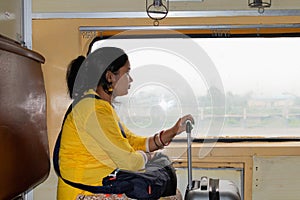 Young Indian woman traveling by train with laggeges. Travelling in public transport in India concepts