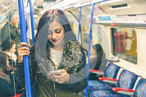 Young indian woman using smart phone in the tube