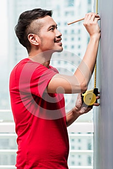 Young indonesian man sizing with tape measure