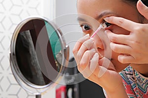 Young indonesian woman putting contact lens in her eye. Health And Eyes Care Concept