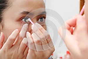 Young indonesian woman putting contact lens in her eye. Health And Eyes Care Concept