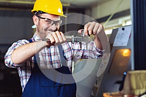 Industrial worker inspector measuring detail with Vernier Caliper