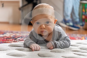 Young infant smiles and plays on his playmat