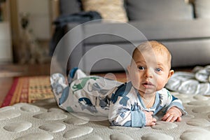 Young infant smiles and plays on his playmat