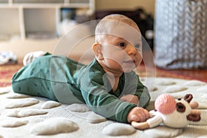 Young infant smiles and plays on his playmat