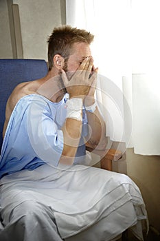 Young injured man crying in hospital room sitting alone crying in pain worried for his health condition