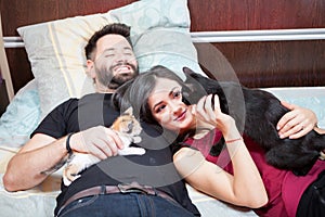 Young inlove couple on the bed with their cats