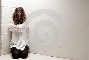 Young insane woman with straitjacket on knees