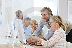 Young instructor assisting seniors in computing class