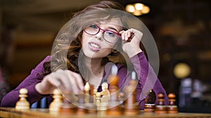 Young intelligent caucasian woman playing chess at home wearing smart casual clothes