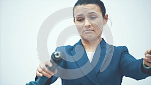 Young intelligent teacher stands on a white background. Holds drill and screwdriver. Has a surprised facial expression