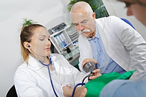 Young internist taking patients blood pressure with coleague