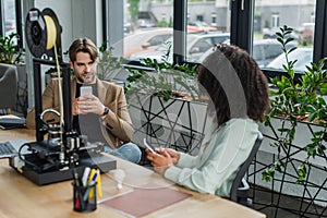 young interracial colleagues sitting with cellphones