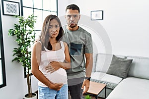 Young interracial couple expecting a baby, touching pregnant belly depressed and worry for distress, crying angry and afraid