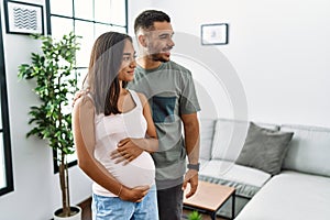 Young interracial couple expecting a baby, touching pregnant belly looking to side, relax profile pose with natural face and