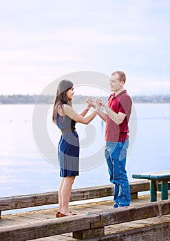 Young interracial couple holding hands standing on dock over lake