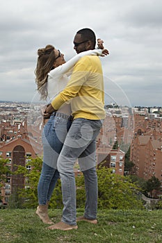 Young interracial couple hugging, laughing and kissing in a park