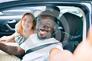 Young interracial couple smiling happy making selfie by the camera at the car