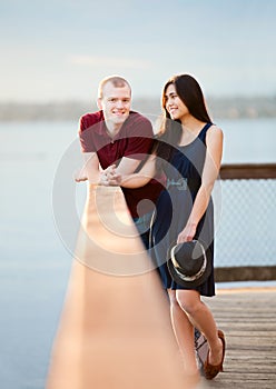 Young interracial couple standing together on wooden pier overlooking lake