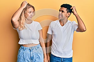 Young interracial couple wearing casual white tshirt confuse and wonder about question