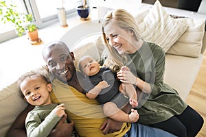 Young interracial family with little children at home.