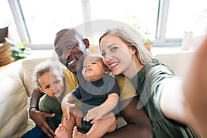 Young interracial family with little children taking selfie.