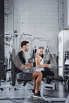 Young interracial sportsmen training with dumbbells