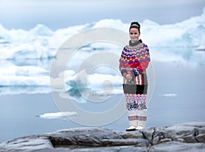 Young inuit woman in traditional clothing posing for photos in a small Greenlandish village.