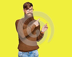 Young irish redhead man wearing casual clothes and glasses pointing aside worried and nervous with both hands, concerned and