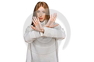 Young irish woman wearing casual winter sweater rejection expression crossing arms doing negative sign, angry face